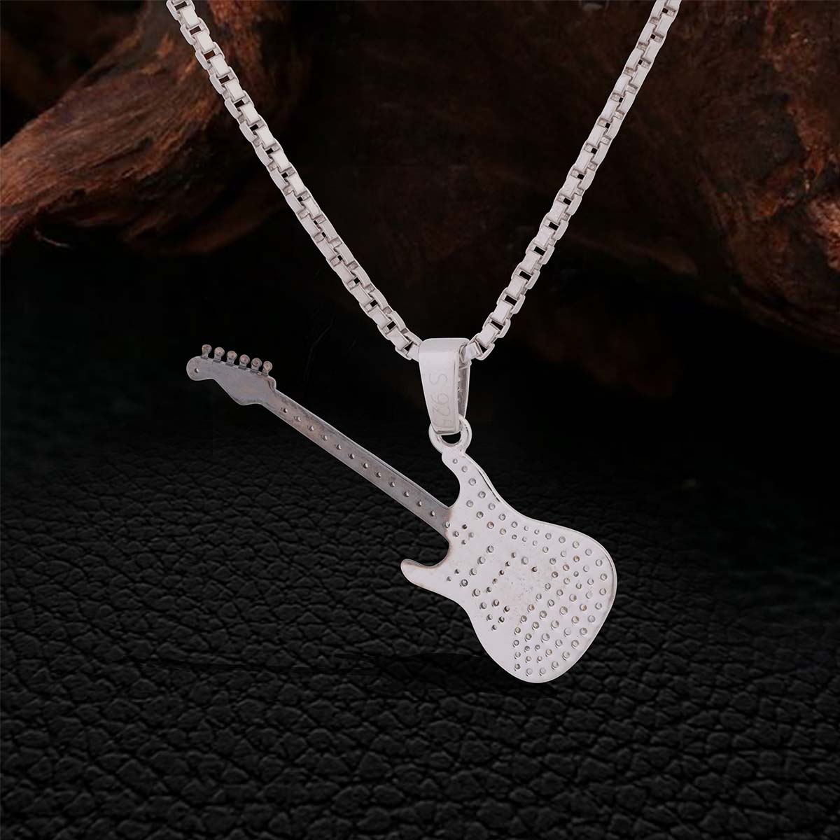 Back Side of a Two Tone Sterling Silver Diamond Studded Iced Out Guitar pendant Necklace with chain on a dark textured background