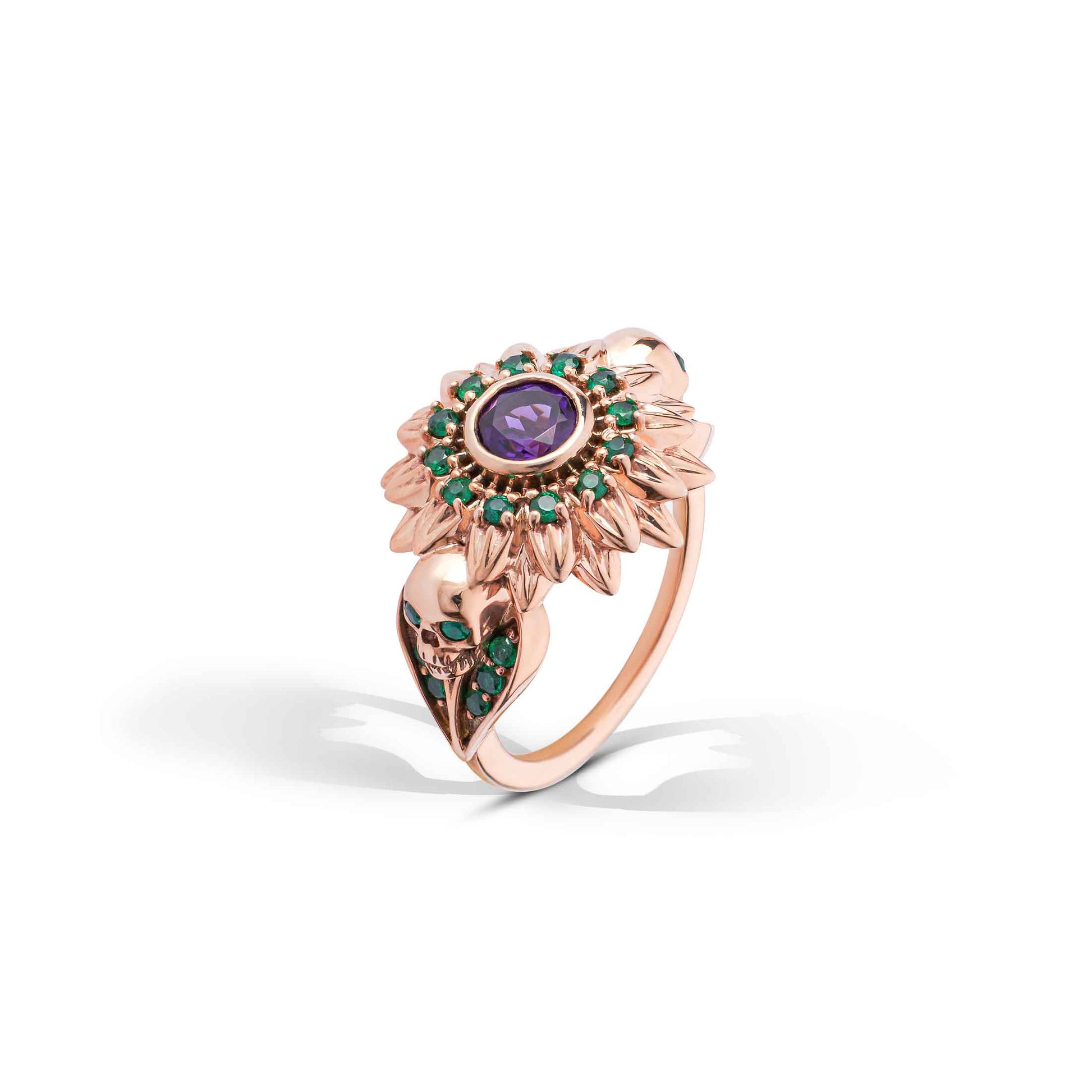 Sunflower-shaped rose gold ring with purple and green gemstones and detailed skull carvings.
