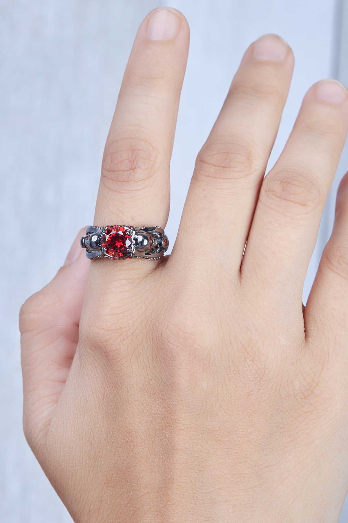 woman's Hand wearing a skull ring with red garnet gemstone
