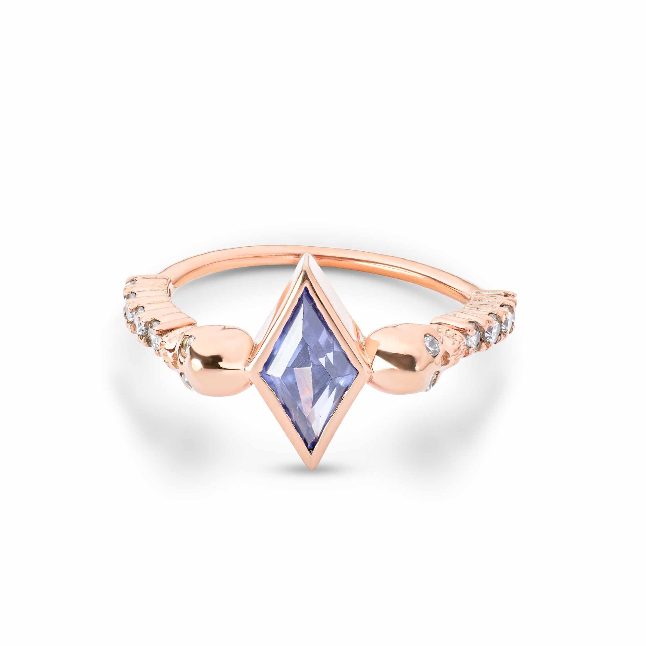Gothic-style rose gold band featuring a bezel-set kite gem and skull-shaped side accents.