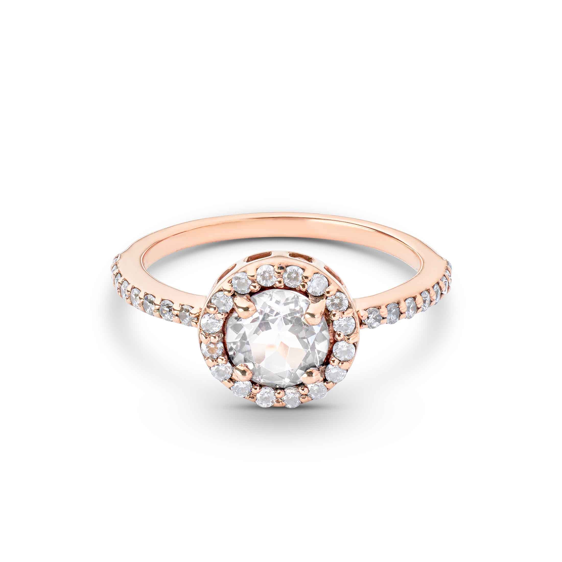 Round center stone surrounded by a diamond halo on a thin rose gold band with pavé accents.
