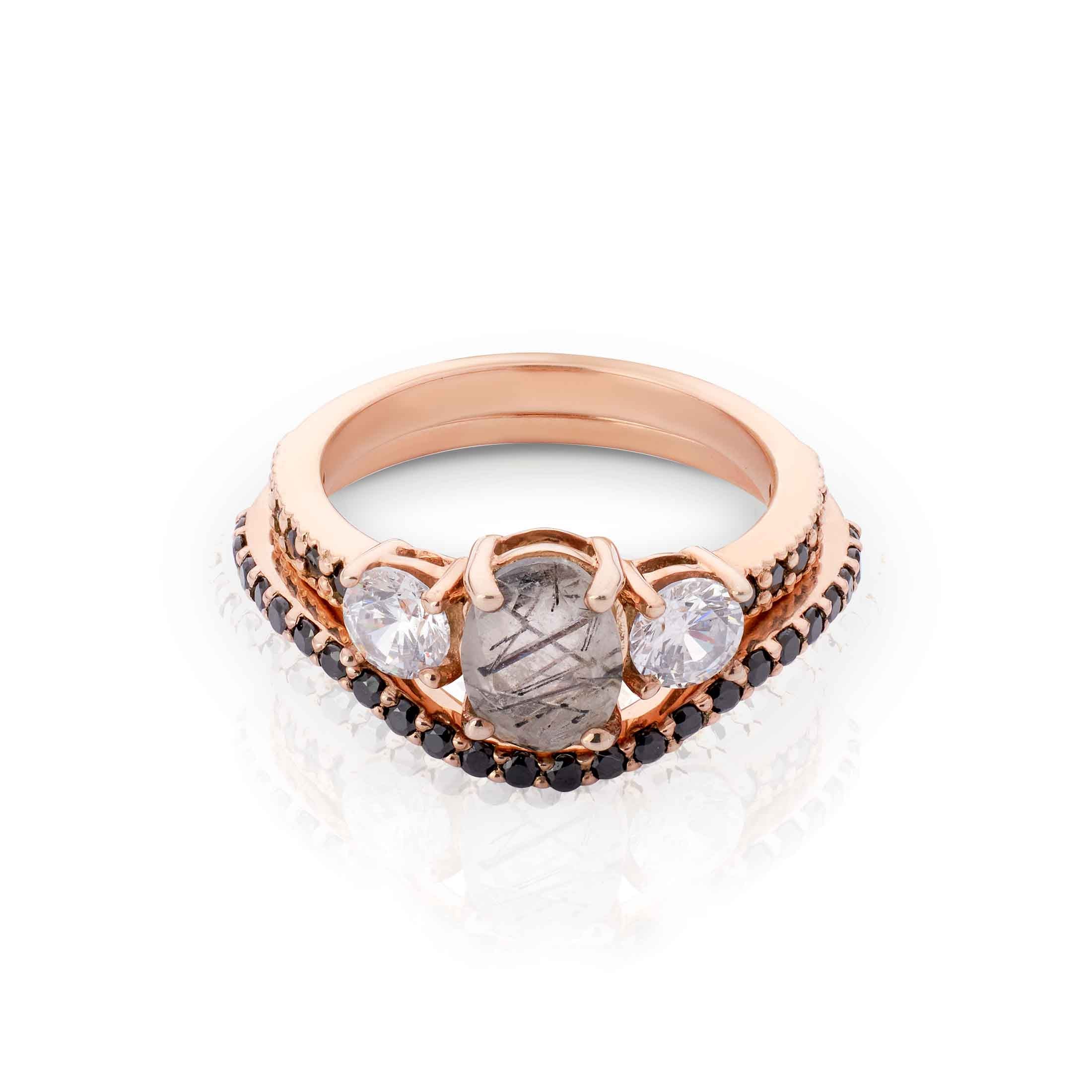 Rose gold ring with central stone and gemstones on a white background
