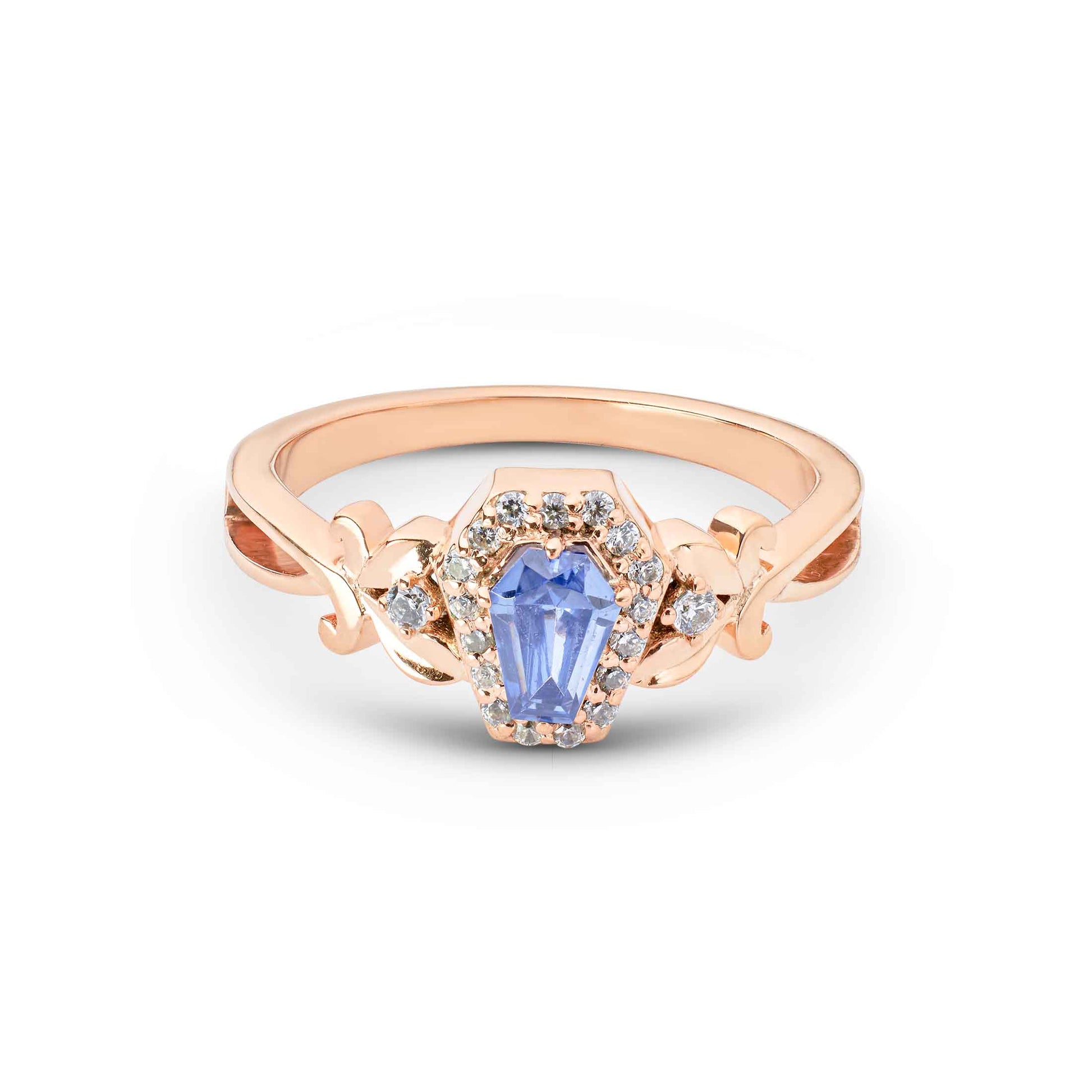 A purple coffin-shaped gemstone set in a rose gold halo mounting with ornate scrollwork sides.