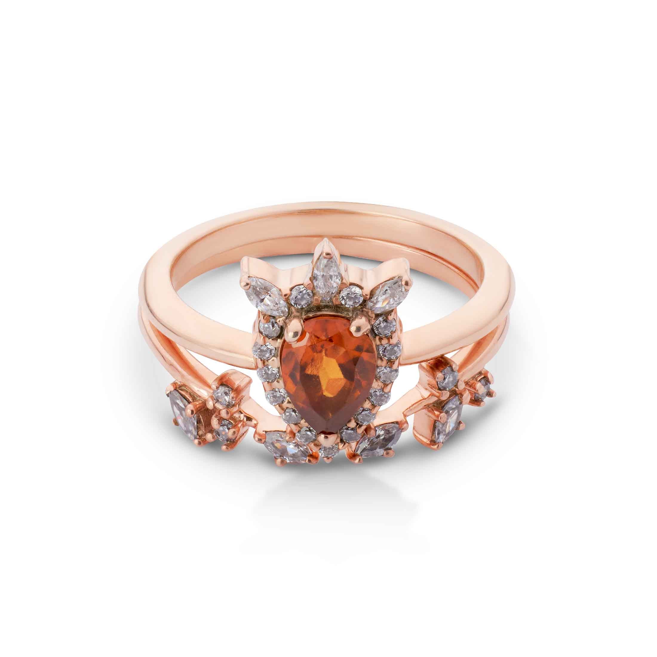 Rose gold ring with a large orange gemstone and smaller diamonds on a white background