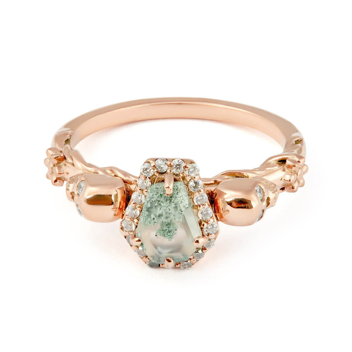 Gothic rose gold ring featuring a green moss agate stone flanked by small gold skulls.