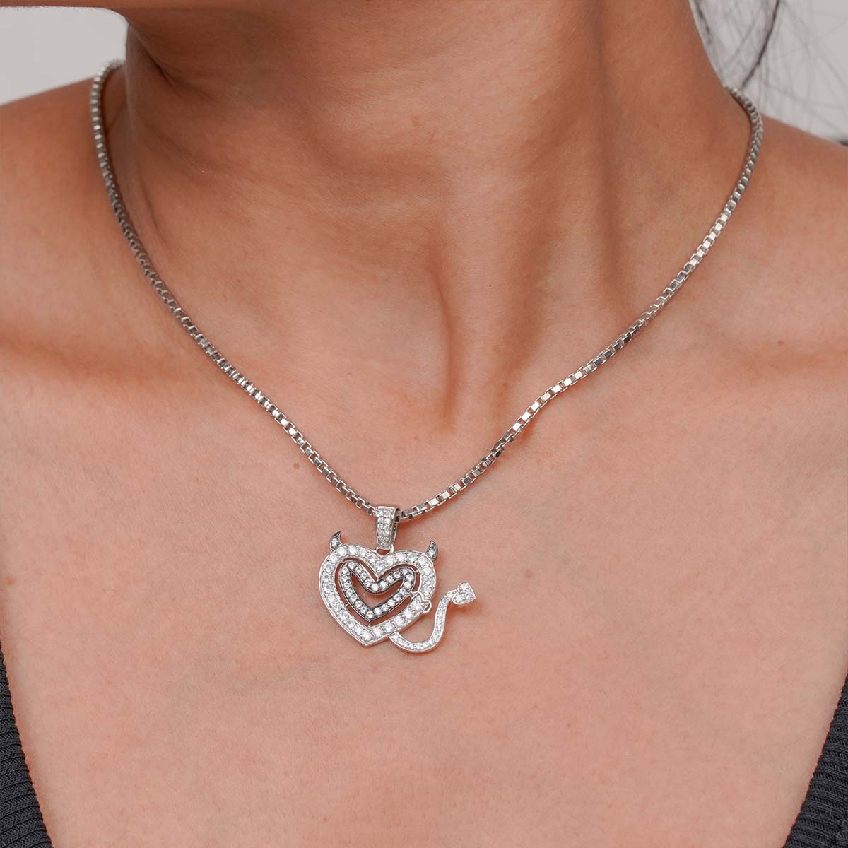 Silver necklace with a heart-shaped pendant on a person's neck