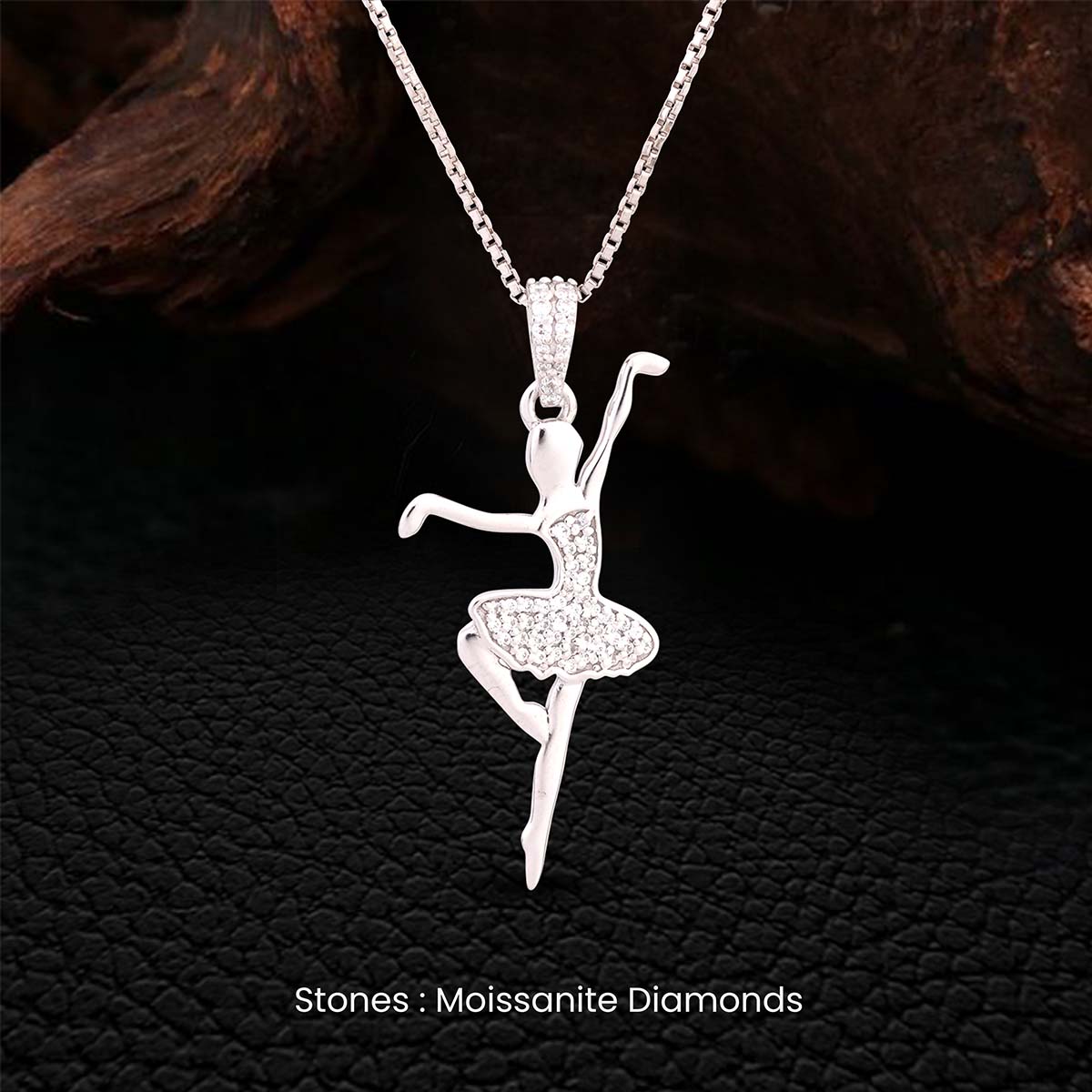 Silver ballerina pendant necklace studded with moissanite diamonds on a dark textured background