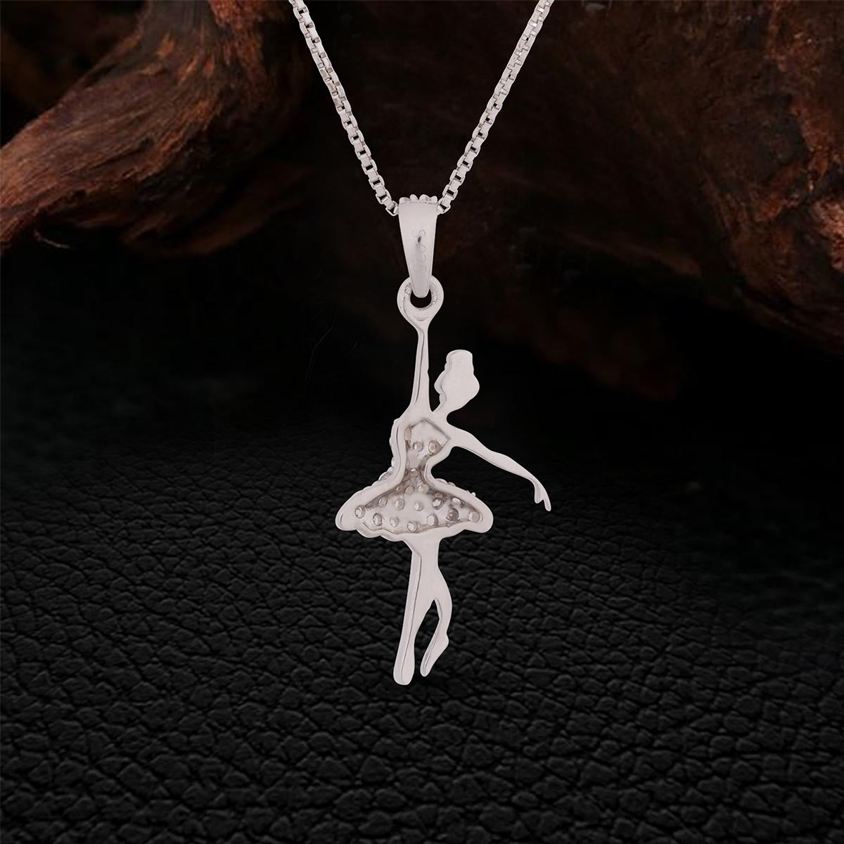 Backside of Silver ballerina pendant on a chain against a dark textured background