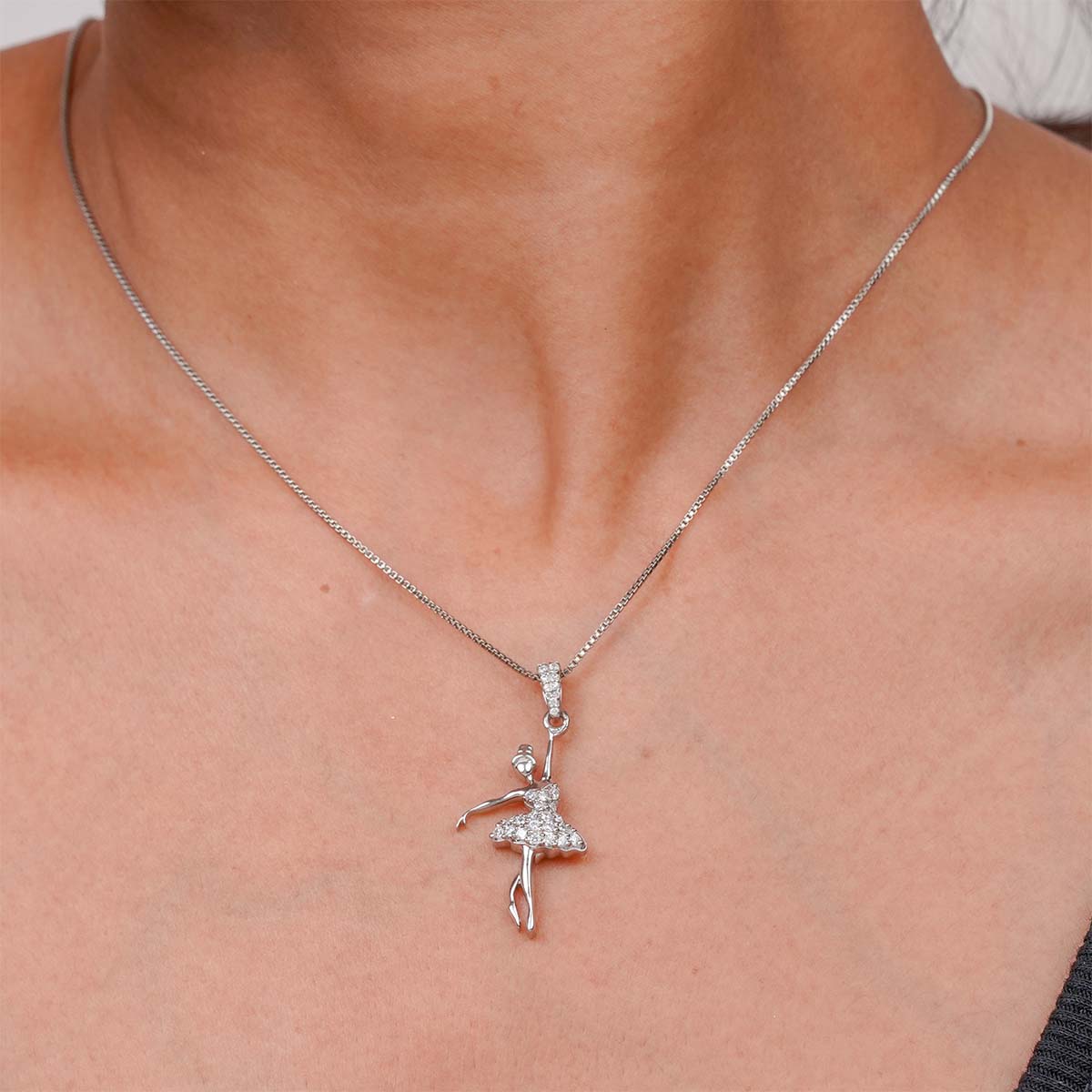 Silver necklace with a ballerina pendant on a person's neck