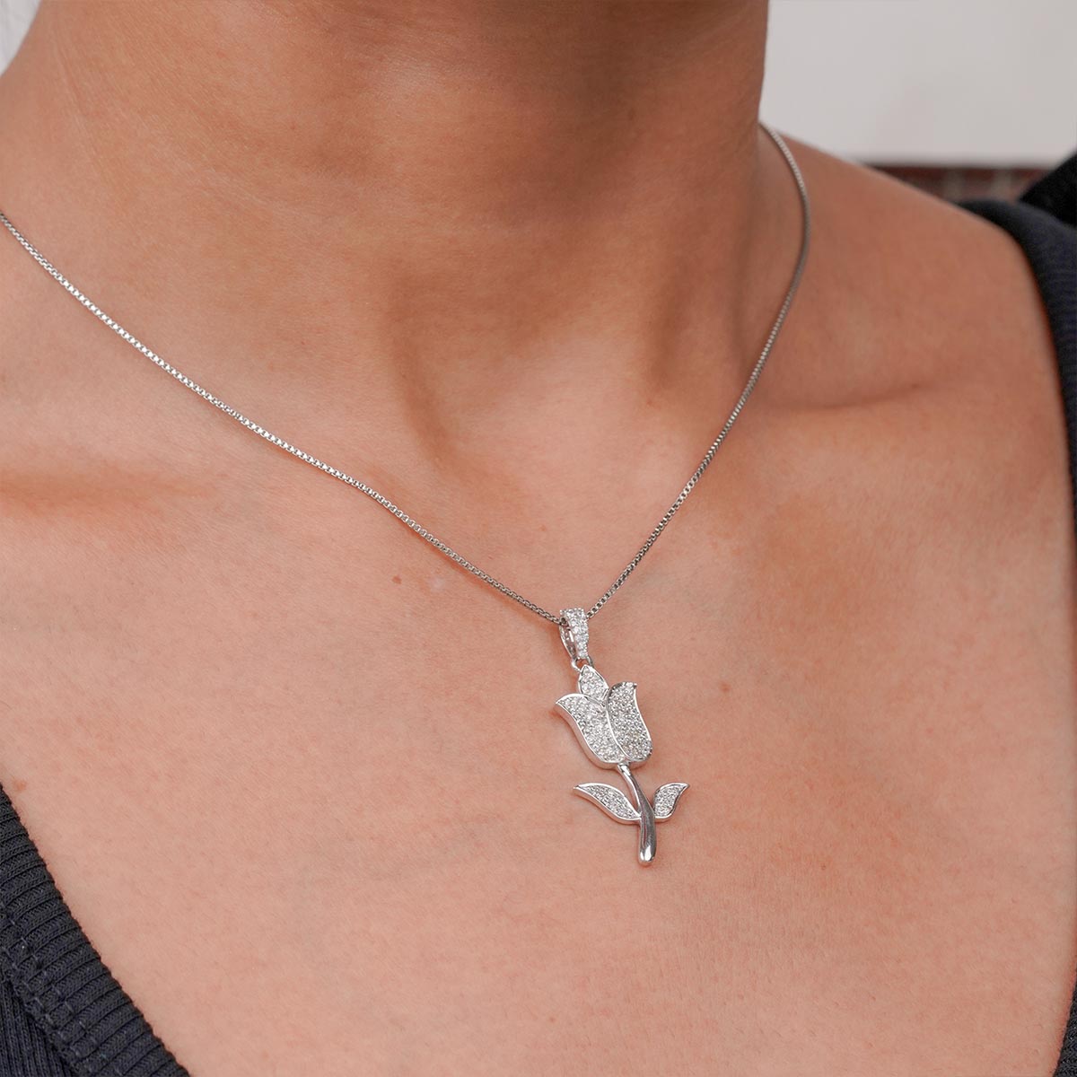 iced out tulip-shaped silver pendant necklace on a person's neck