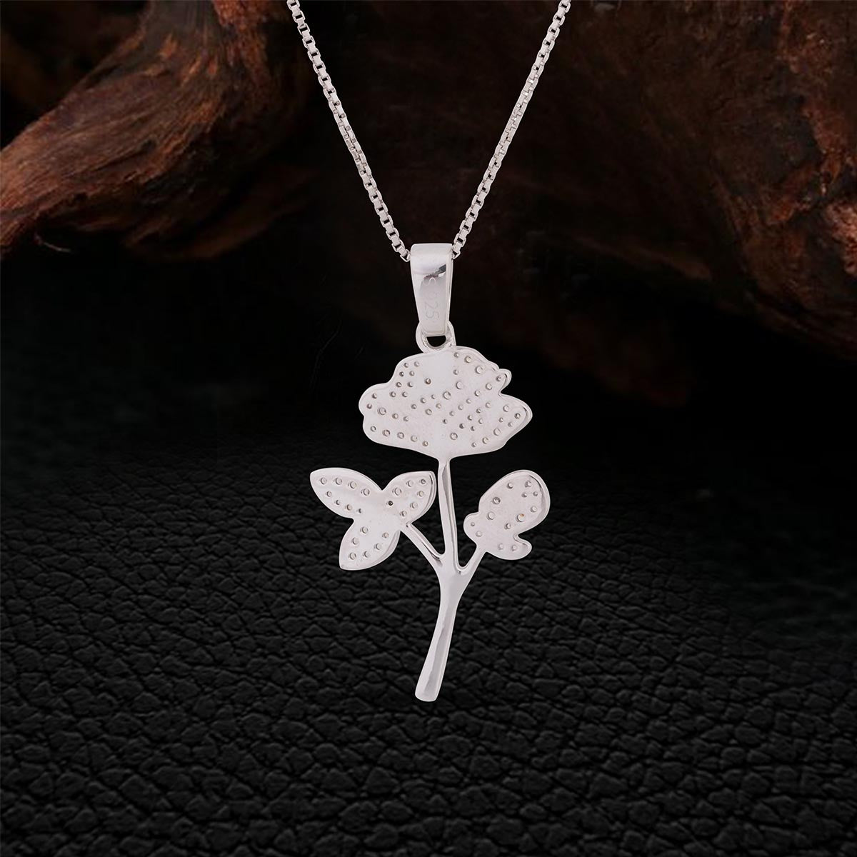 Backside of Sterling Silver necklace with Rose Flower pendant on a dark textured background