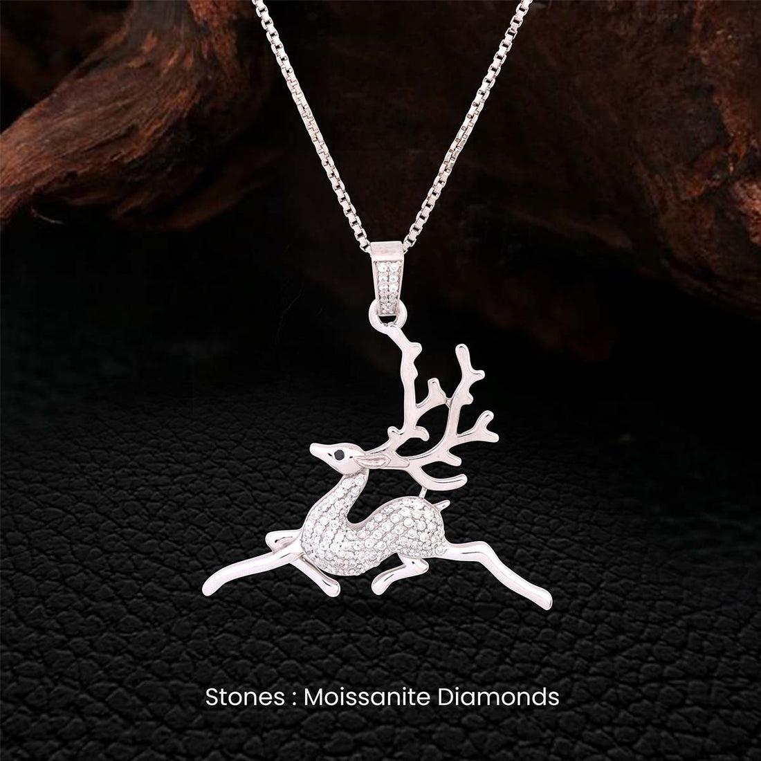 Silver reindeer pendant necklace with moissanite diamonds on a dark textured background