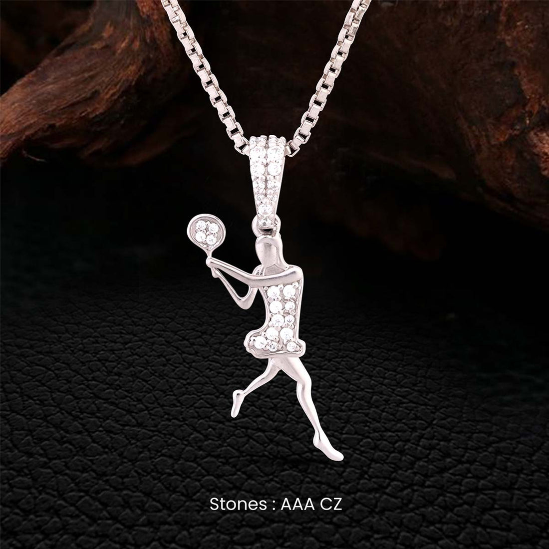 Silver pendant of a woman playing tennis on a dark textured background