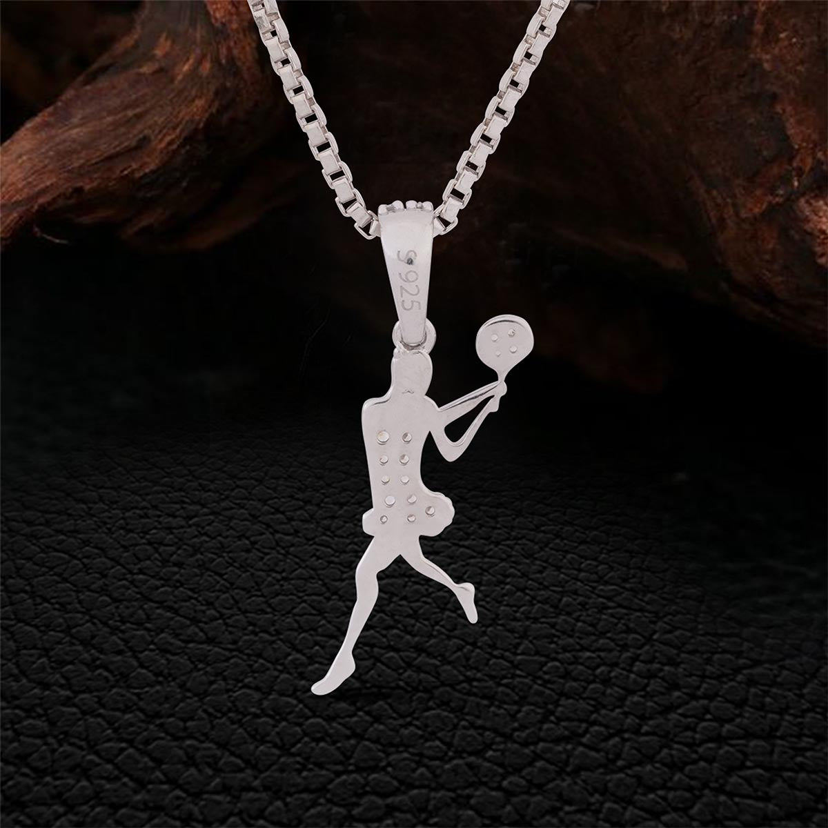 backside of Sterling Silver tennis player pendant necklace on a dark textured background