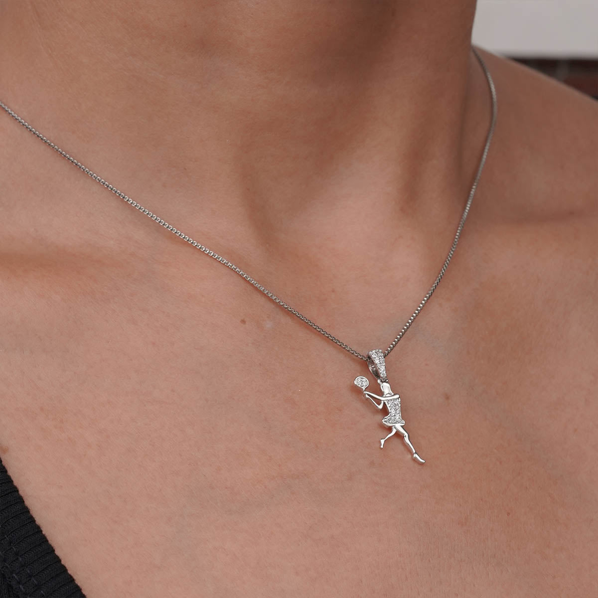 Silver tennis player pendant necklace on a girl's neck