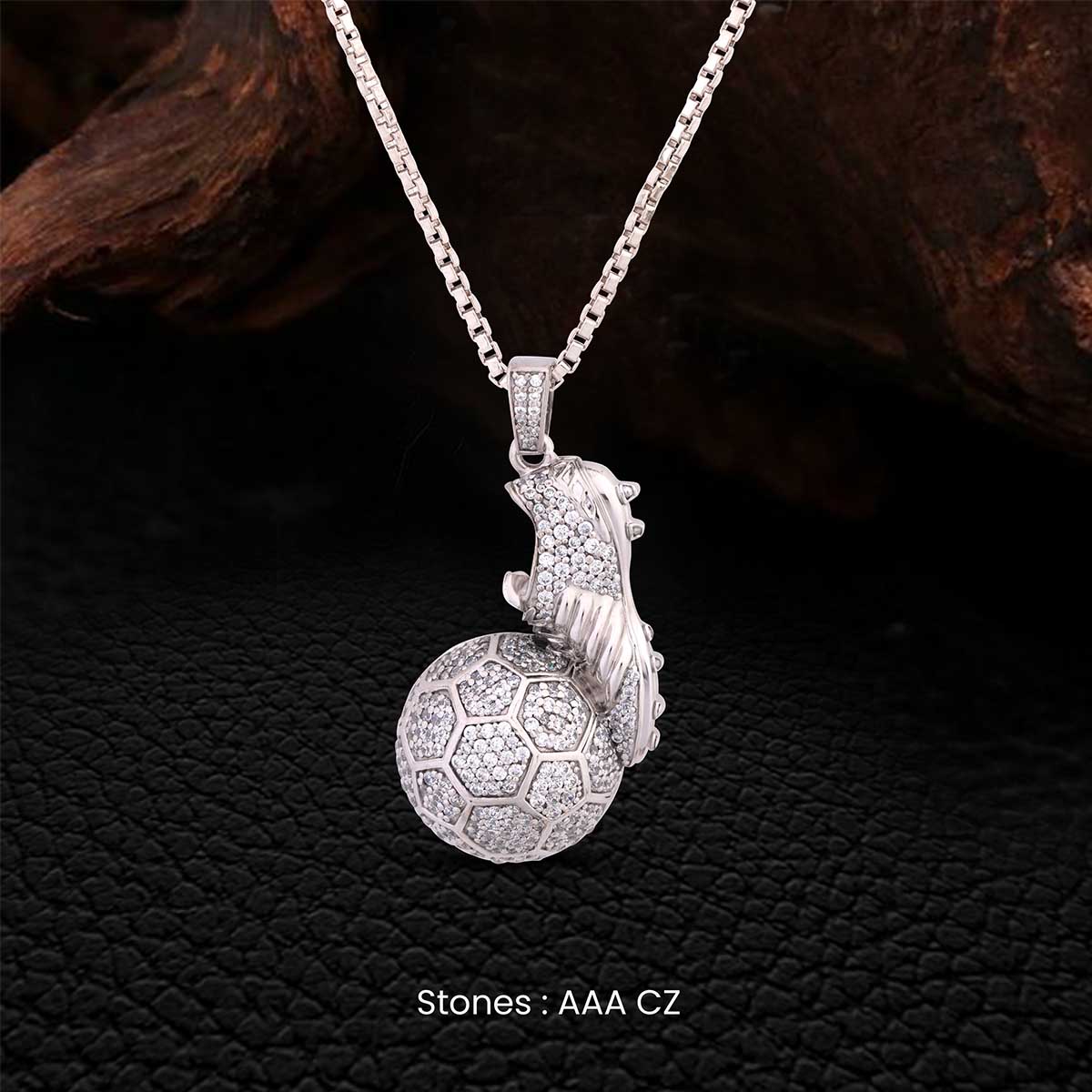 Silver pendant with a soccer ball and cleat design on a dark background