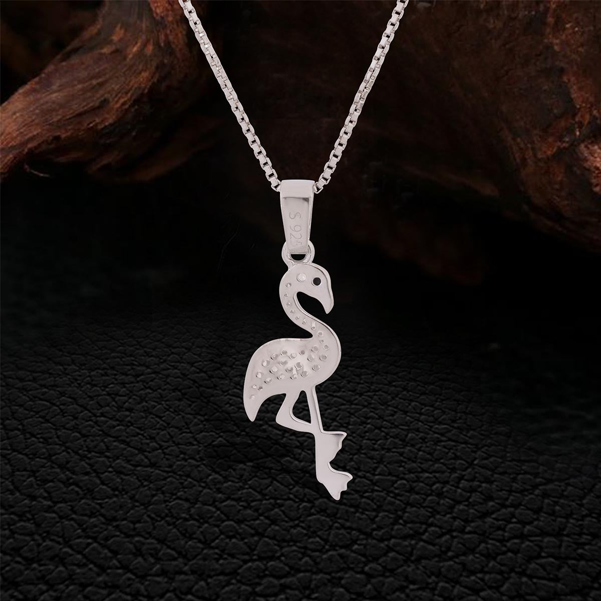 backside of sterling Silver flamingo pendant necklace on a dark textured background