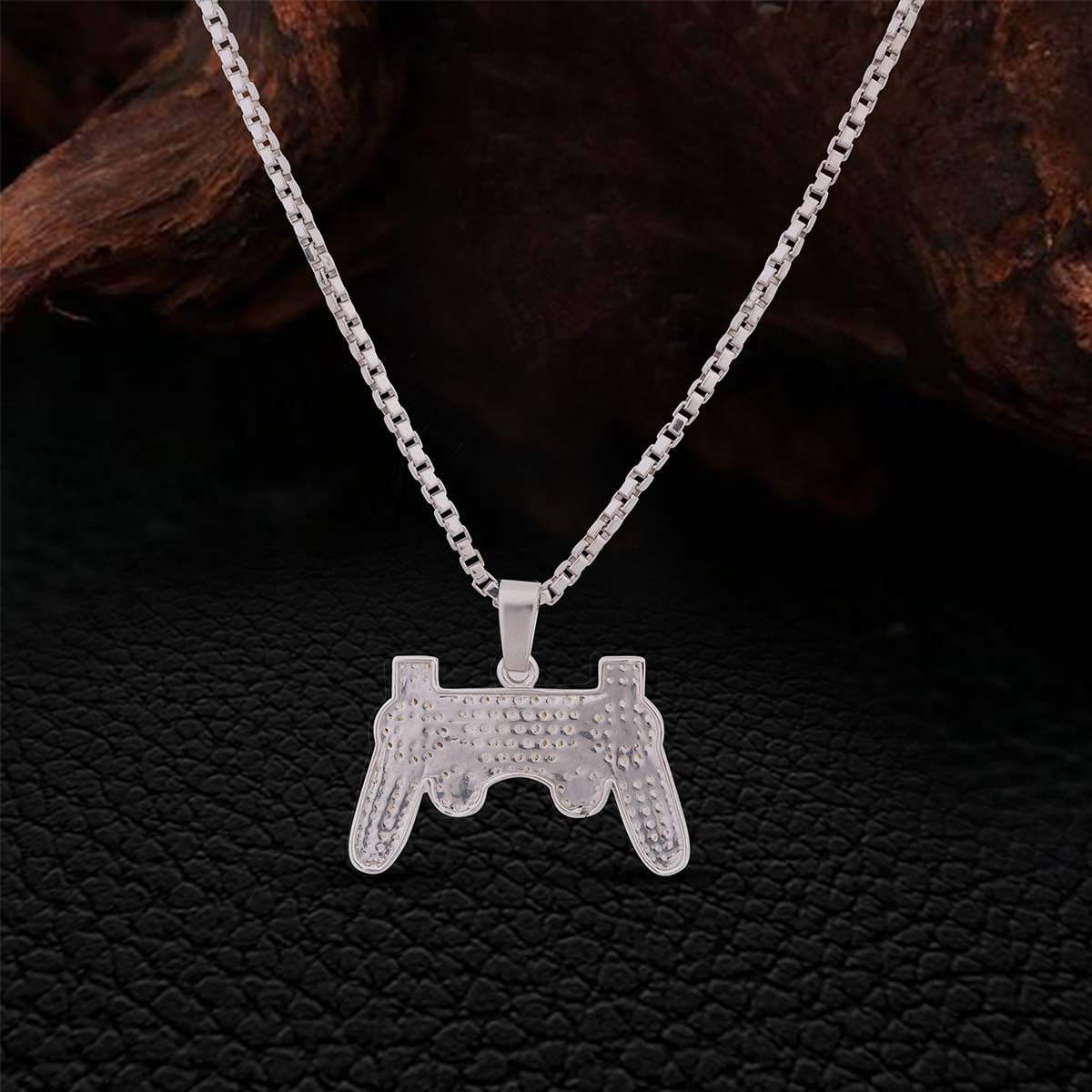 Backside of Sterling Silver pendant shaped like a gaming controller on a chain against a dark background