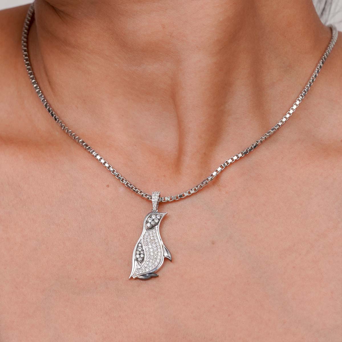 Two tone penguin pendant necklace on a person's neck