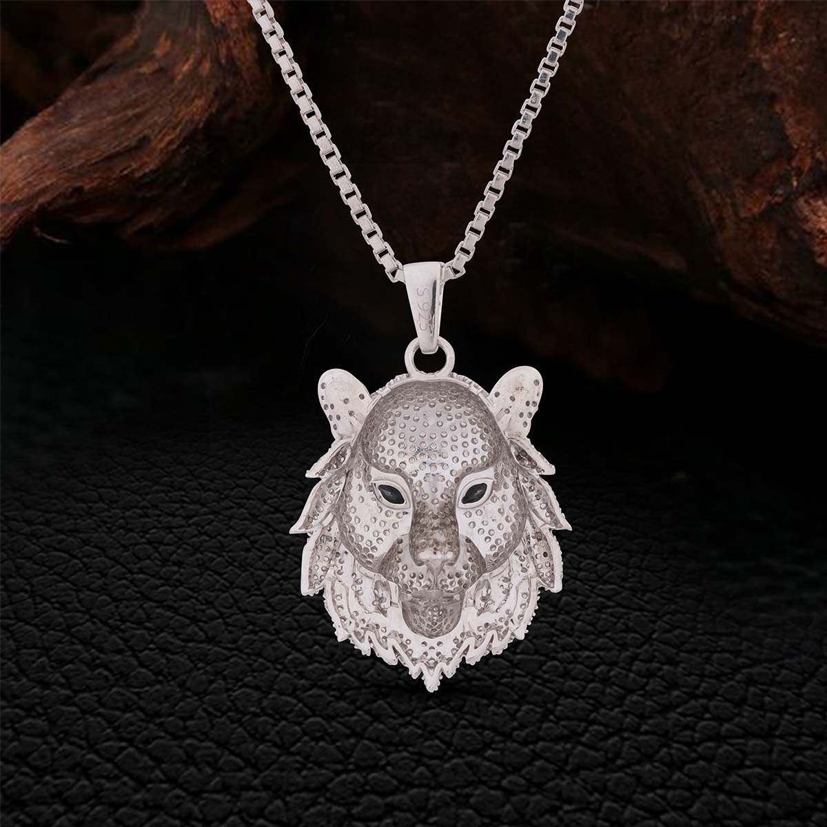 Backside of a 925 Sterling Silver lion head pendant Necklace on a chain against a dark textured background