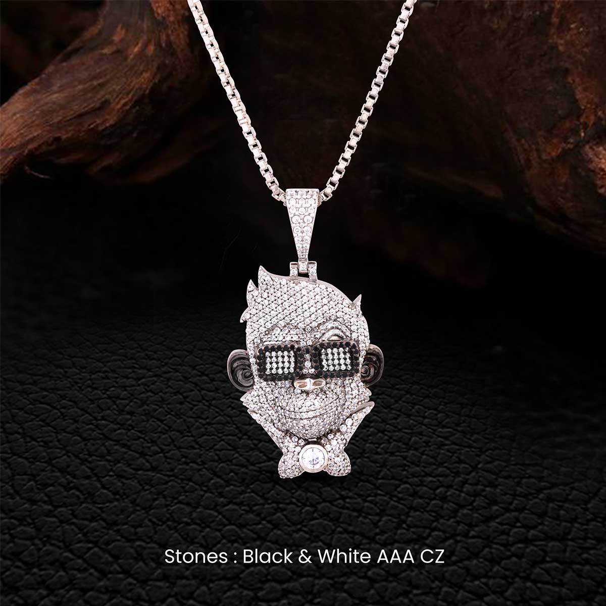 Silver monkey pendant necklace with black and white stones on a dark textured background