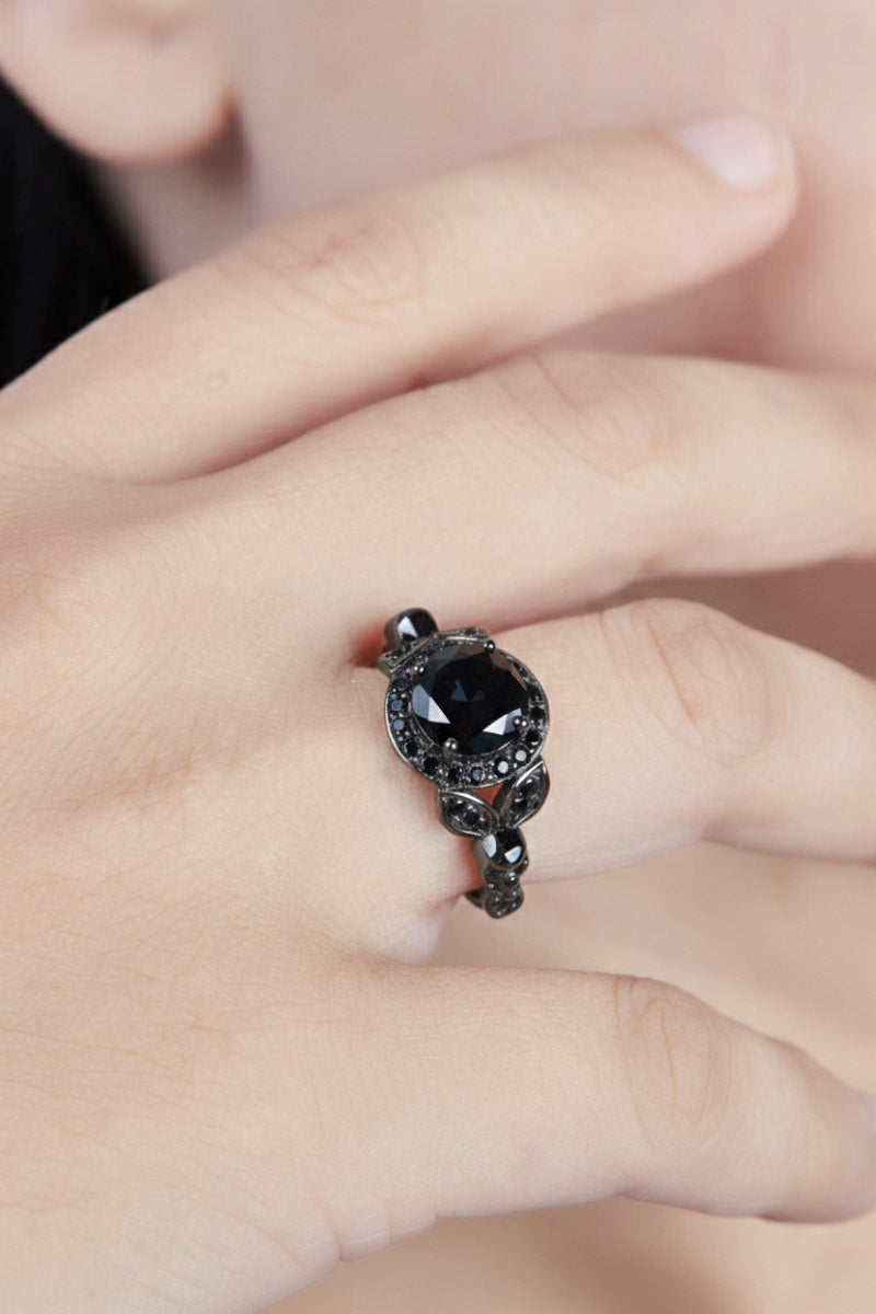 Close-up of a hand wearing a black skull ring with leaf design.