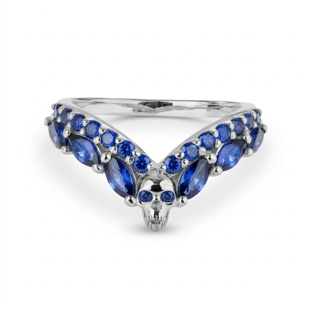 Sterling silver V-shaped chevron ring enhancer with blue sapphire gemstones and a central skull detail, a striking piece of gothic style wedding jewelry.