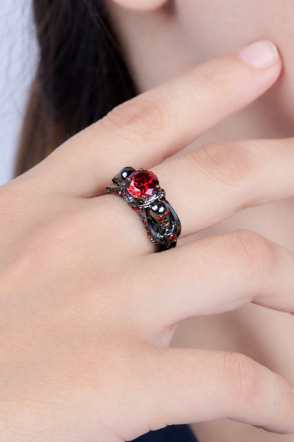 Close-up of a hand wearing a skull ring with a red gemstone.