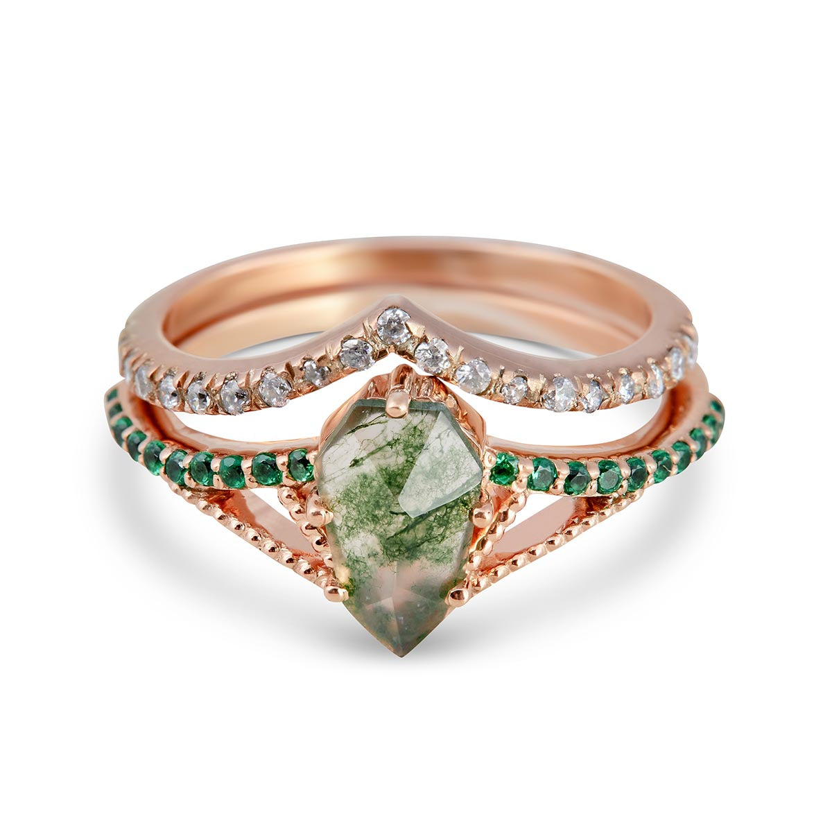 Close-up of a bohemian rose gold ring stack with a geometric green stone and chevron-shaped bands.
