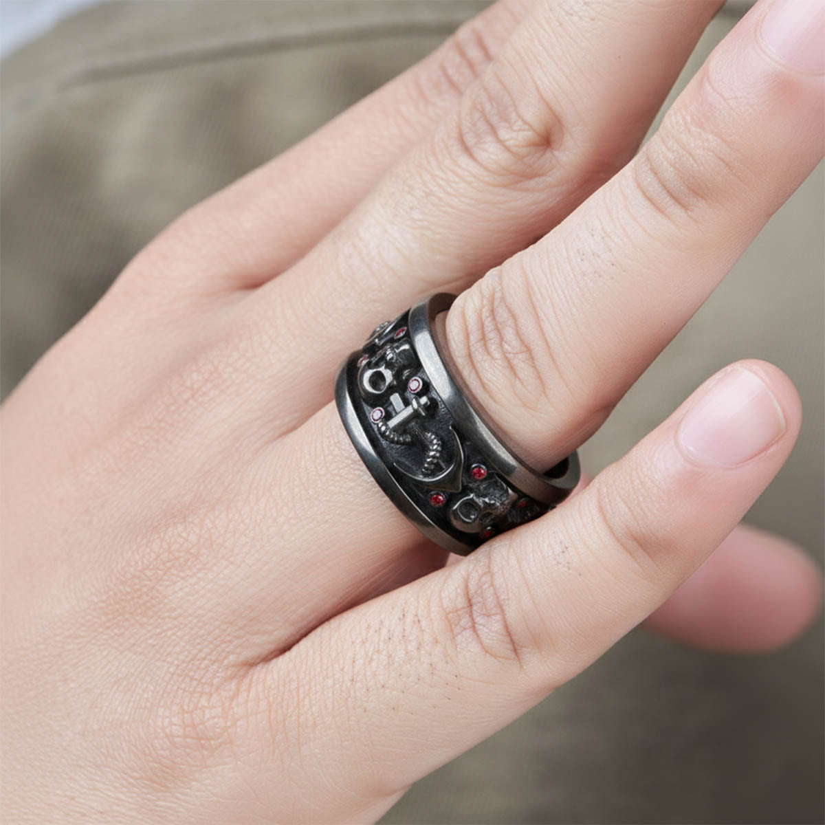 Close-up of a hand wearing a black skull ring with anchor design
