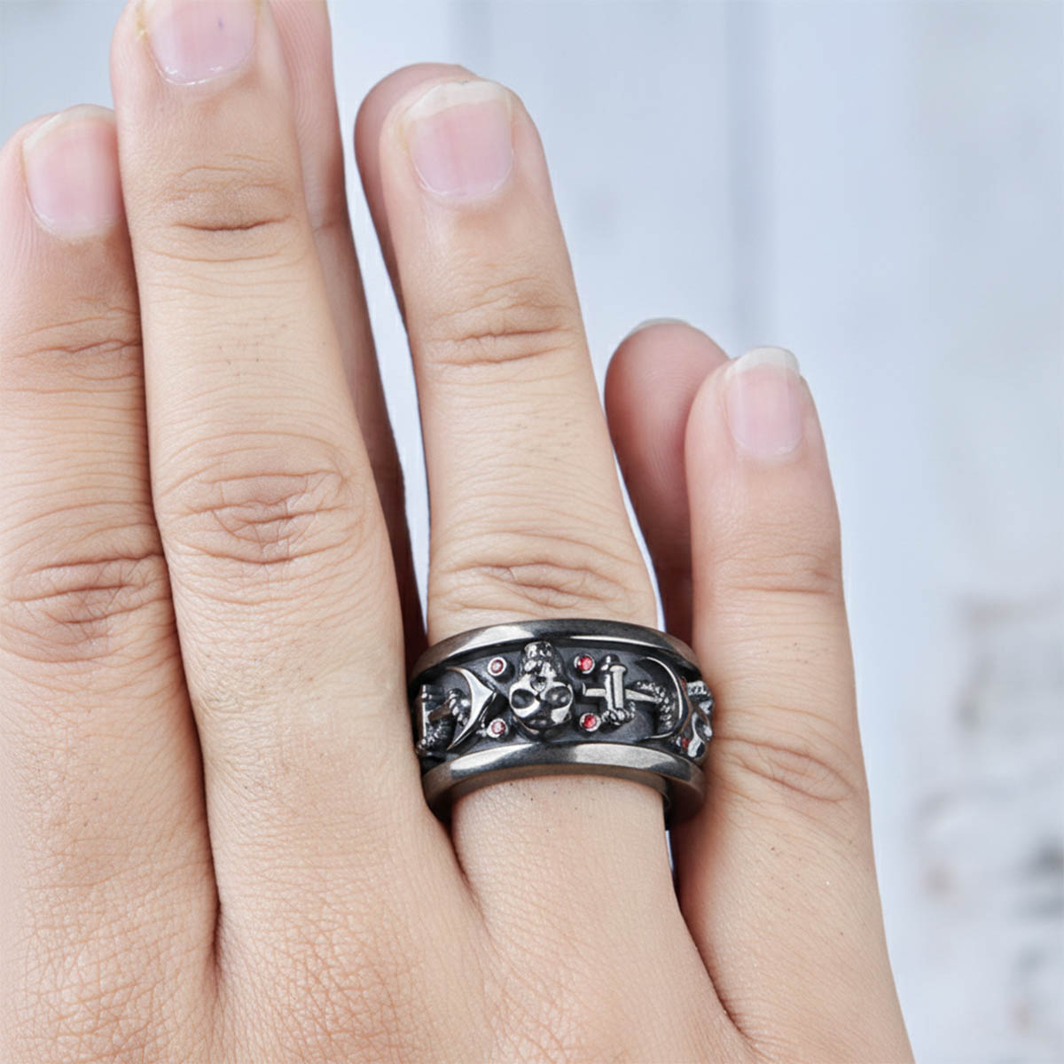 A person wearing black wedding band with skull and anchor motifs 