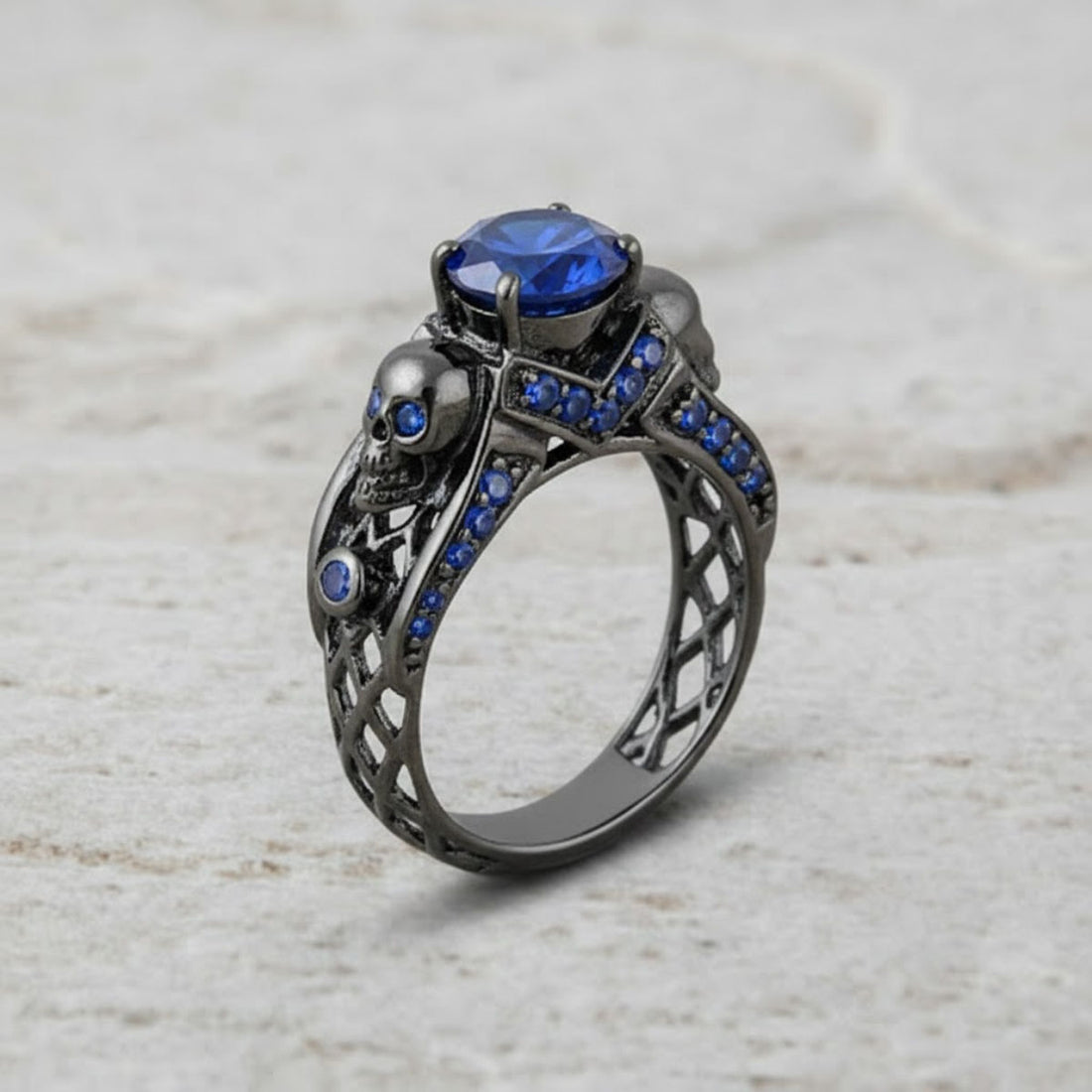black skull ring with blue sapphire gemstones and criss cross mesh design band