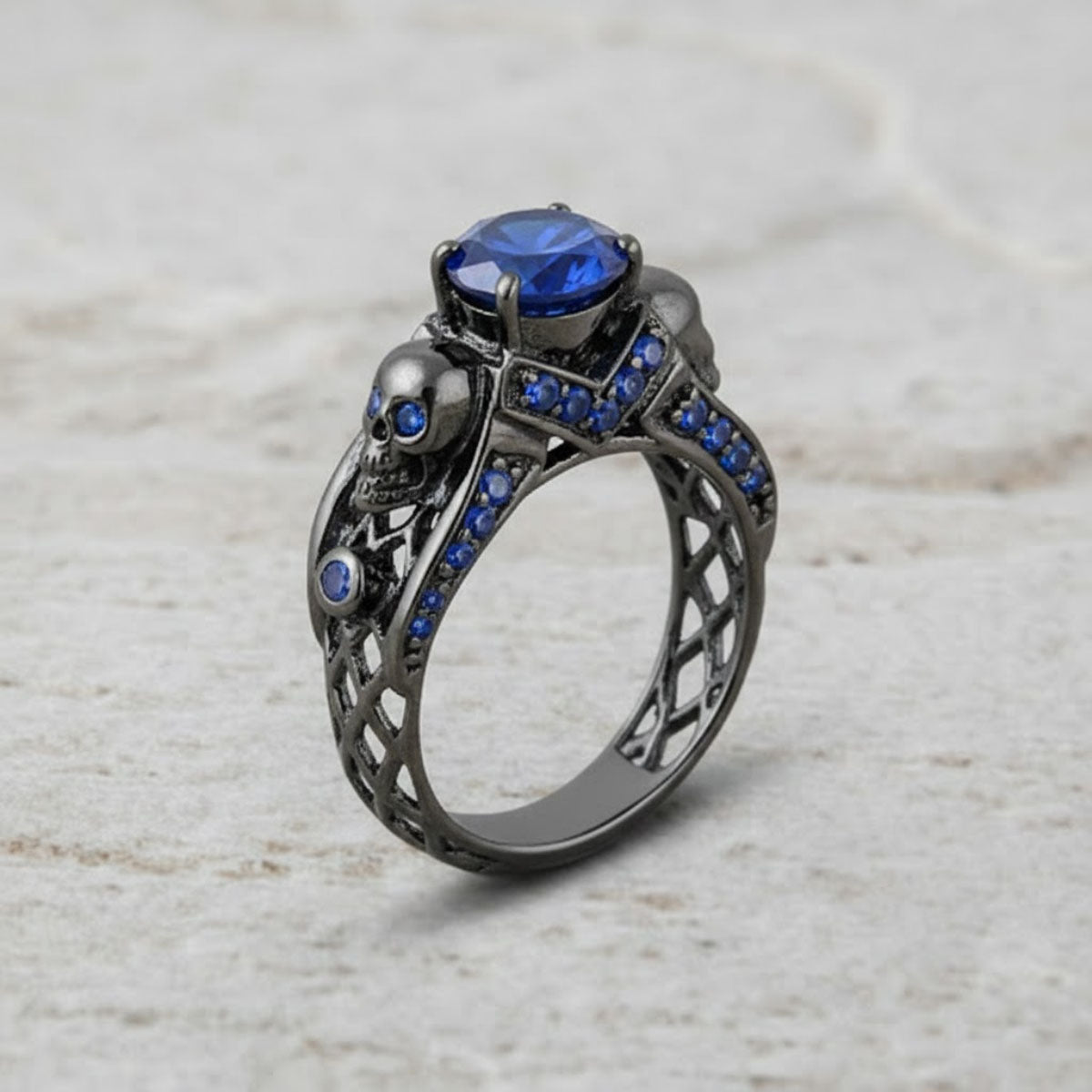 black skull ring with blue sapphire gemstones and criss cross mesh design band
