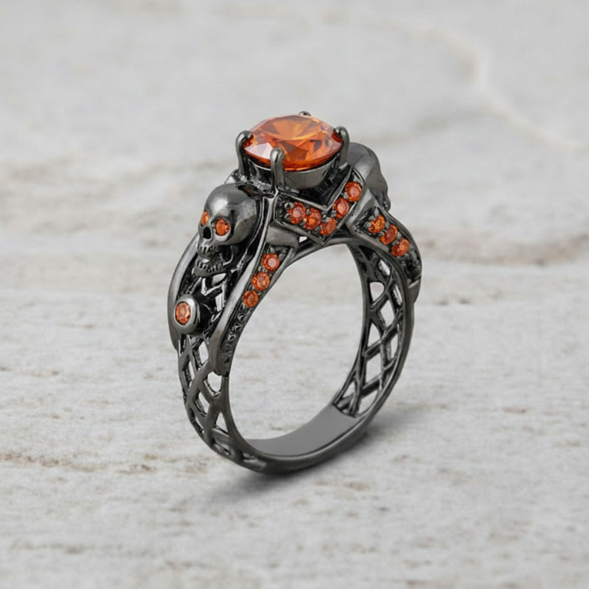 black skull ring with orange sapphire gemstones and criss cross mesh design band