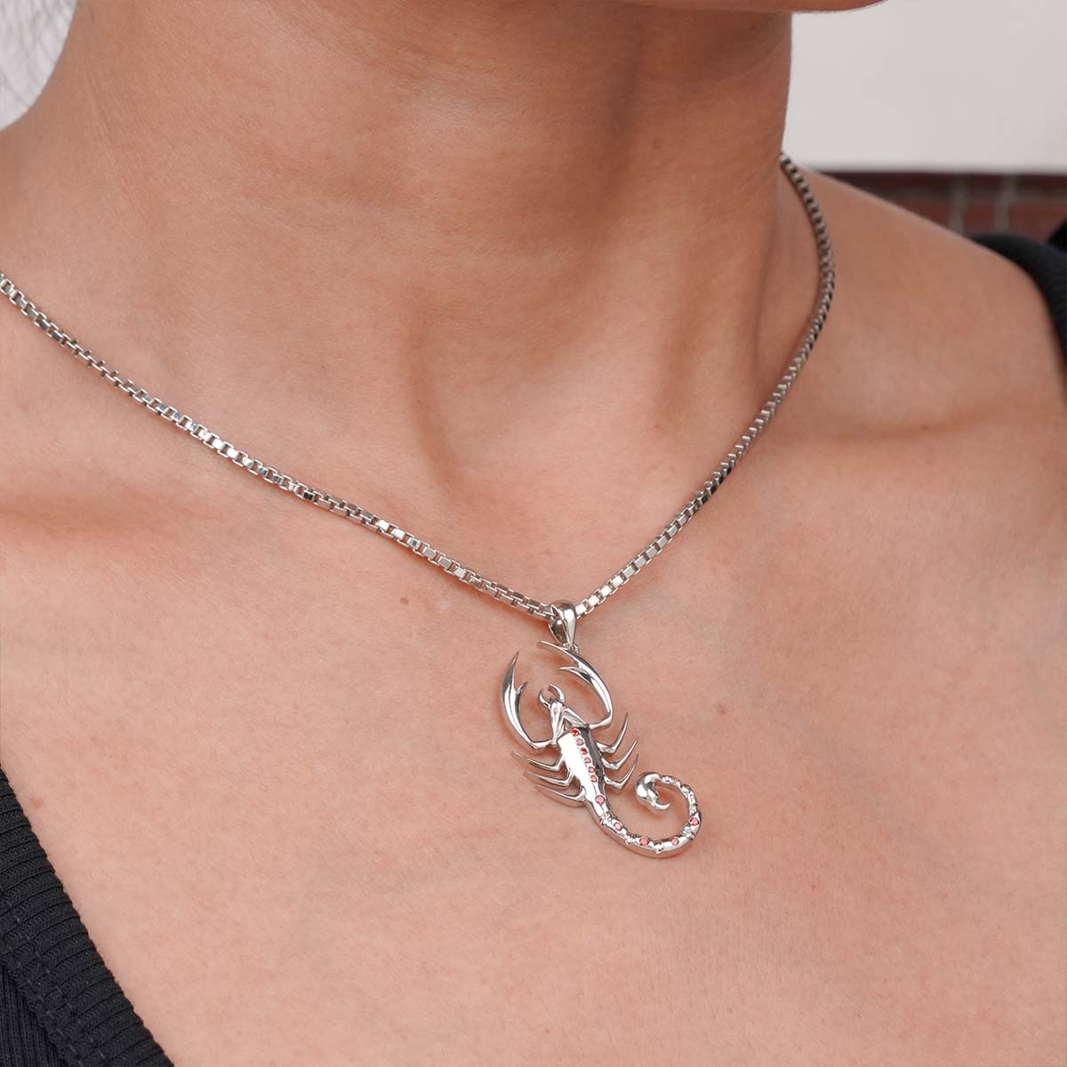 Silver scorpion pendant necklace on a person's neck