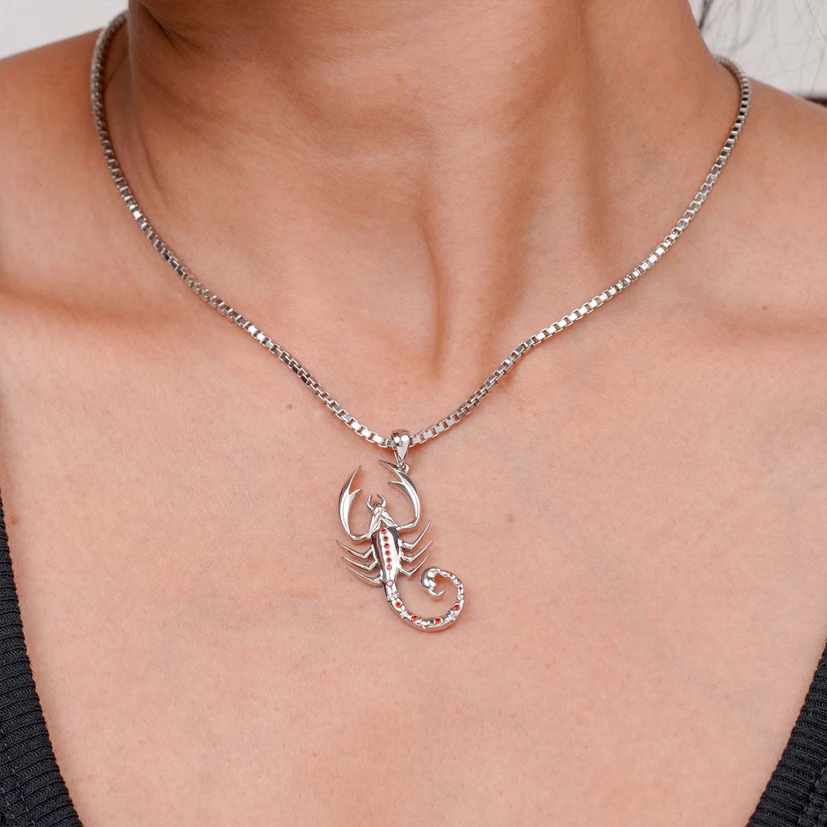 Silver scorpion pendant necklace on a person's neck