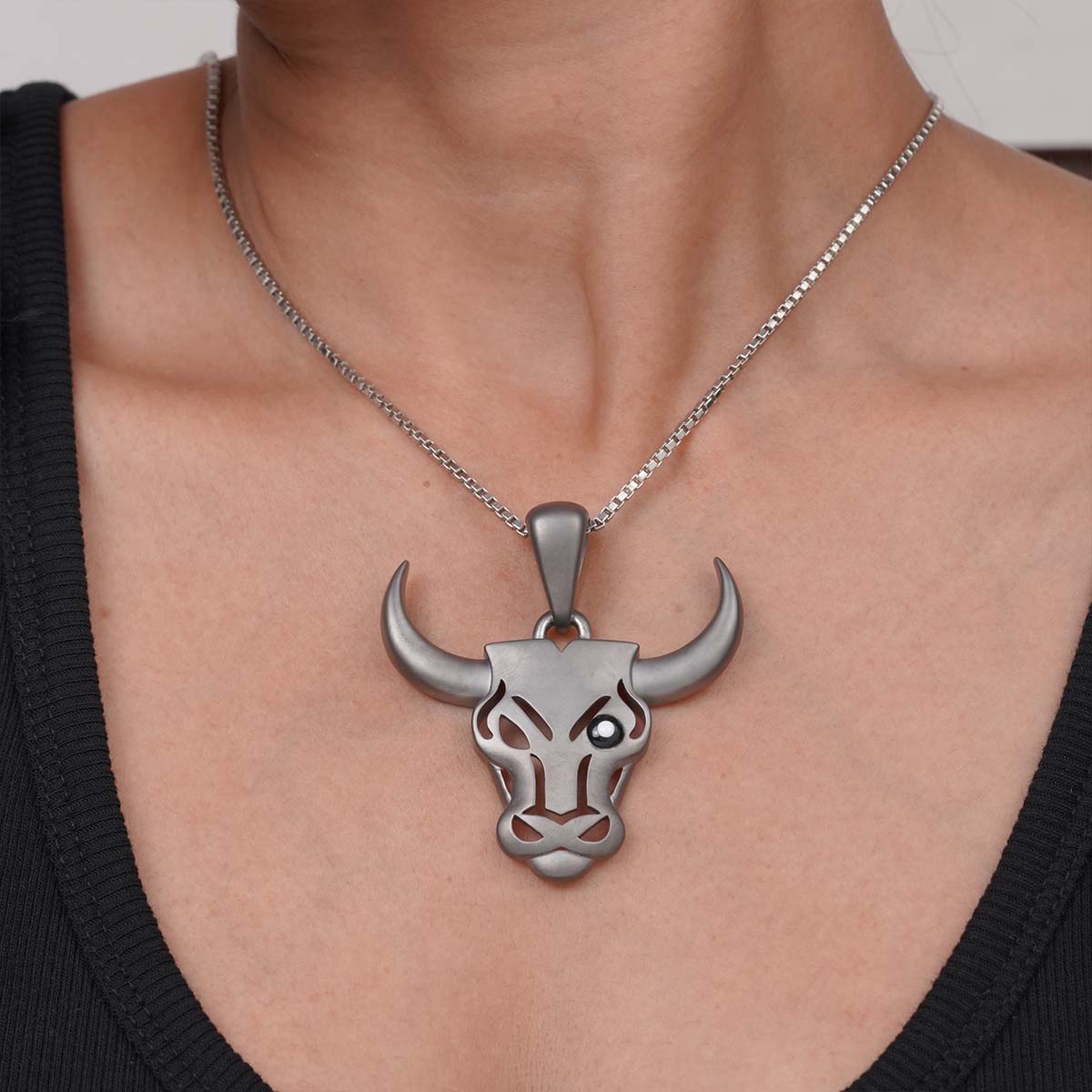 Silver bull head pendant necklace on a person wearing a black top.