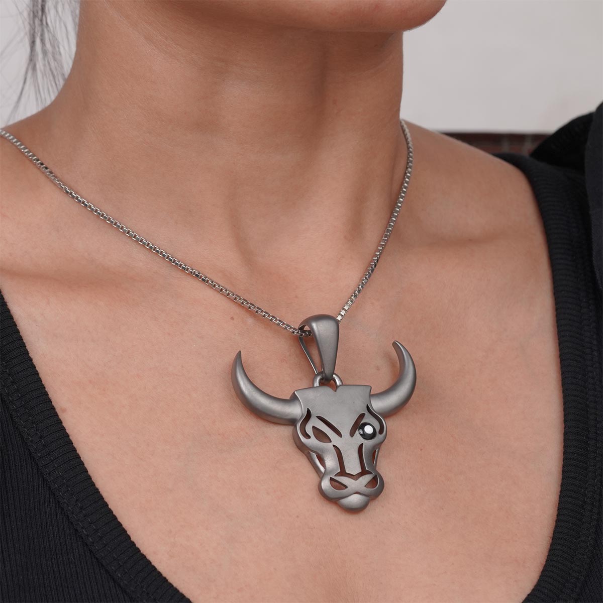 Sterling Silver bull head pendant necklace on a person wearing a black top.