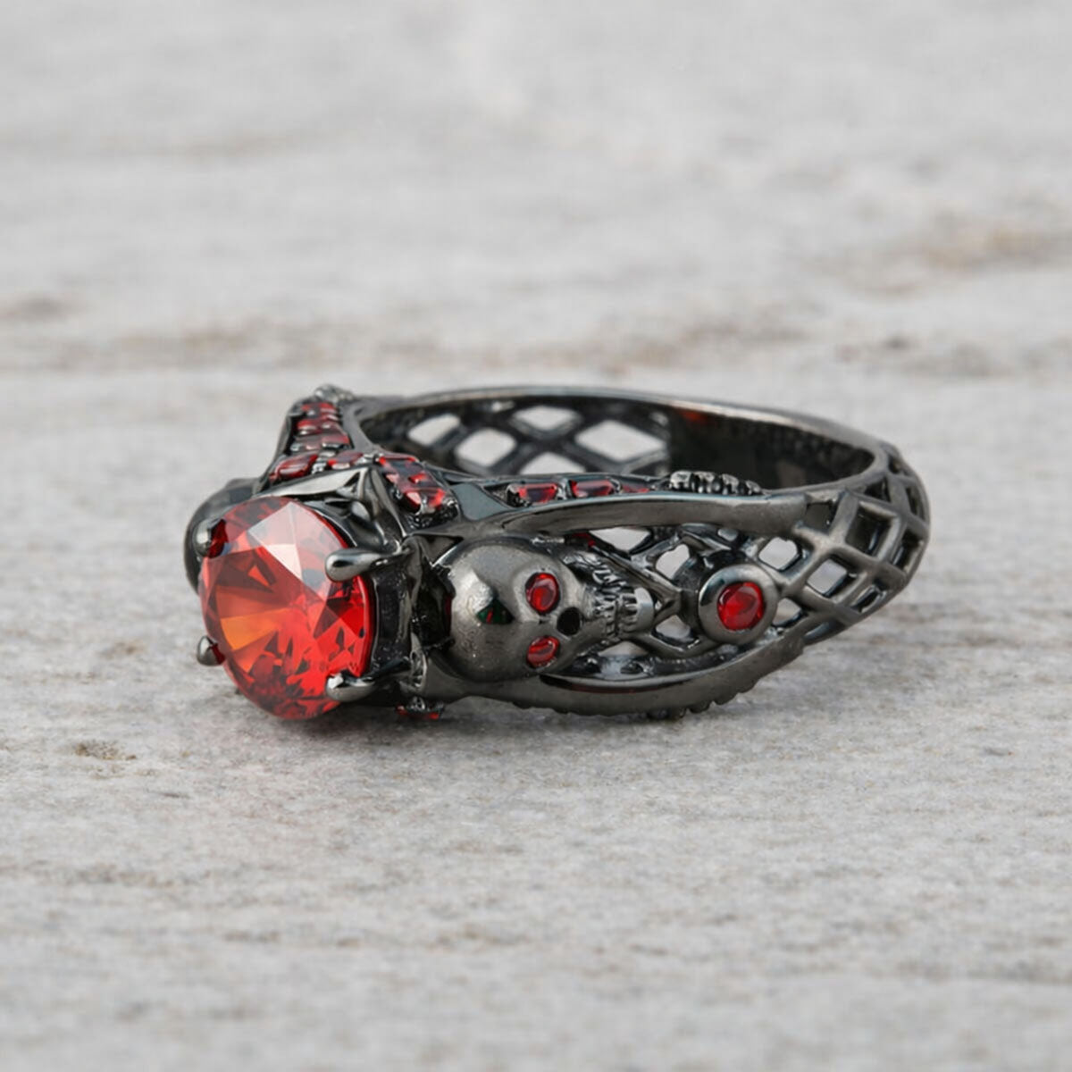 black skull ring with red garnet gemstones and criss cross mesh design band