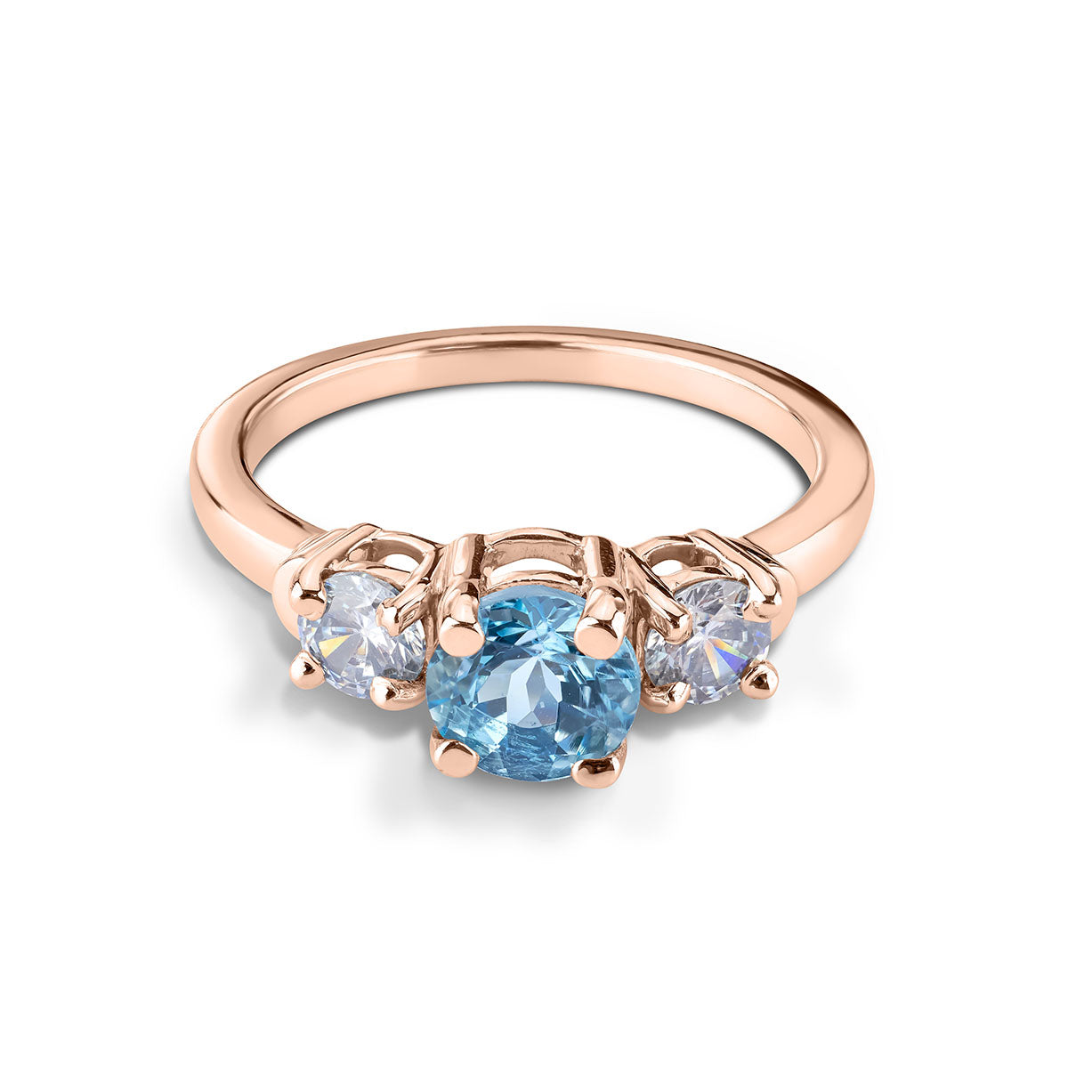 Three-stone ring with a round light blue center gem and white side stones on a rose gold band.